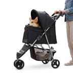 Pet owner using a black three-wheel pet stroller outdoors